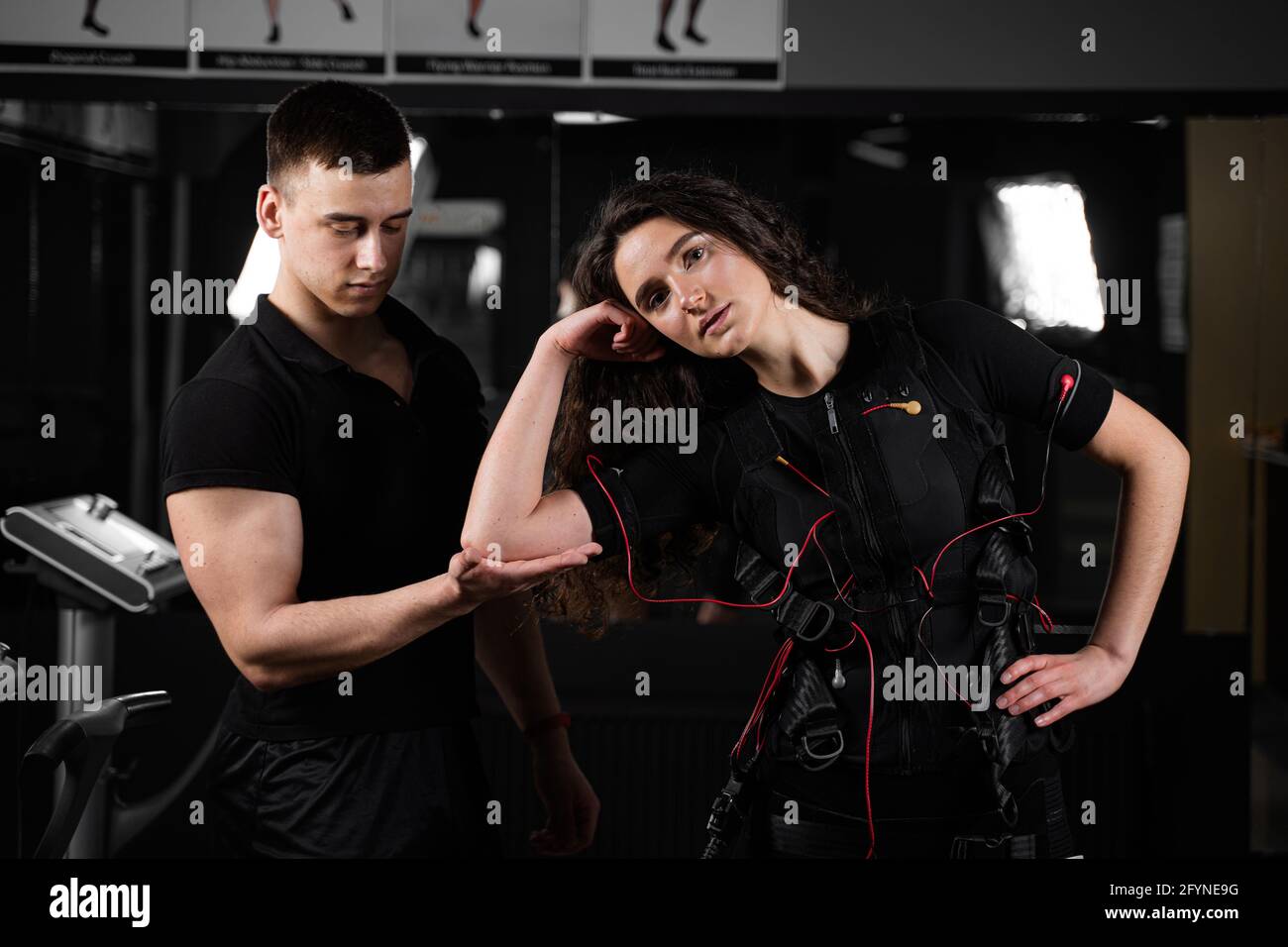 Man trainer trains a girl in an EMS suit in the gym. Electrical ...