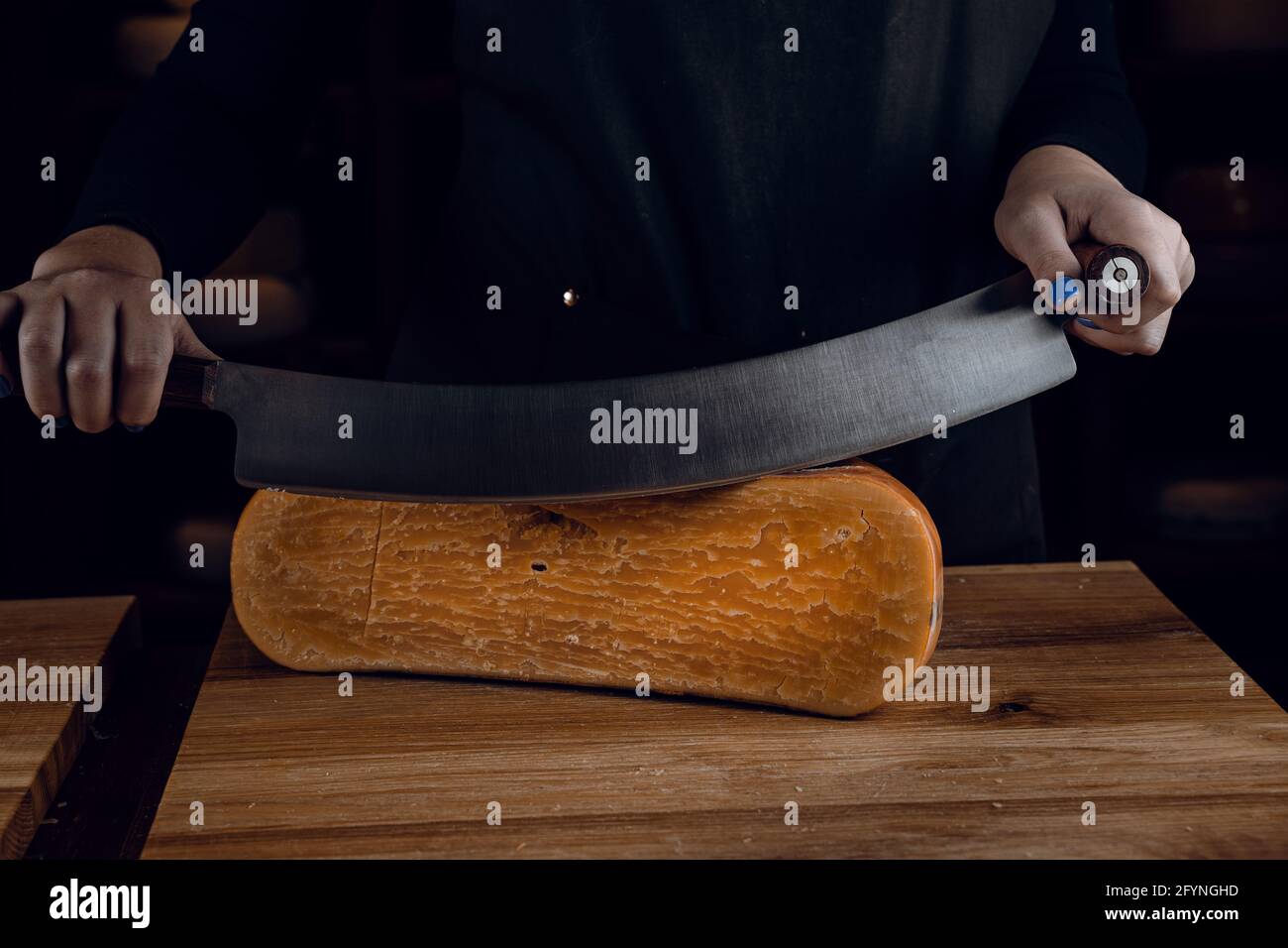 Slicing aged cheese parmesan with crystals using a cheesy dutch knife