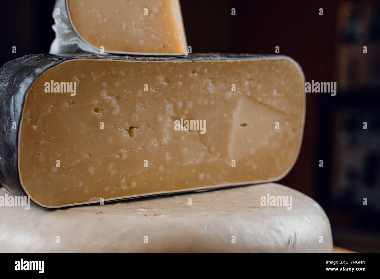 Goat cheese wheel and big pieces of it. Mix of cheeses from goat milk