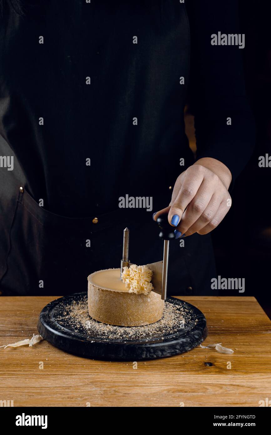 Shaving tete de moine cheese using girolle knife. Monks head. Variety of  Swiss semi-hard cheese made from cows milk Stock Photo - Alamy