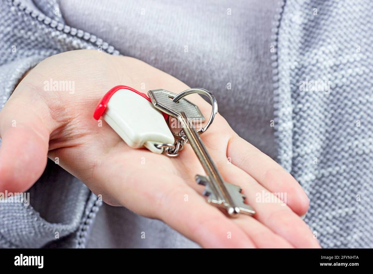 Woman hands holding the keychain with the keys and small house key ring close up. Apartment renter, real estate ownership, property purchase concept. Stock Photo