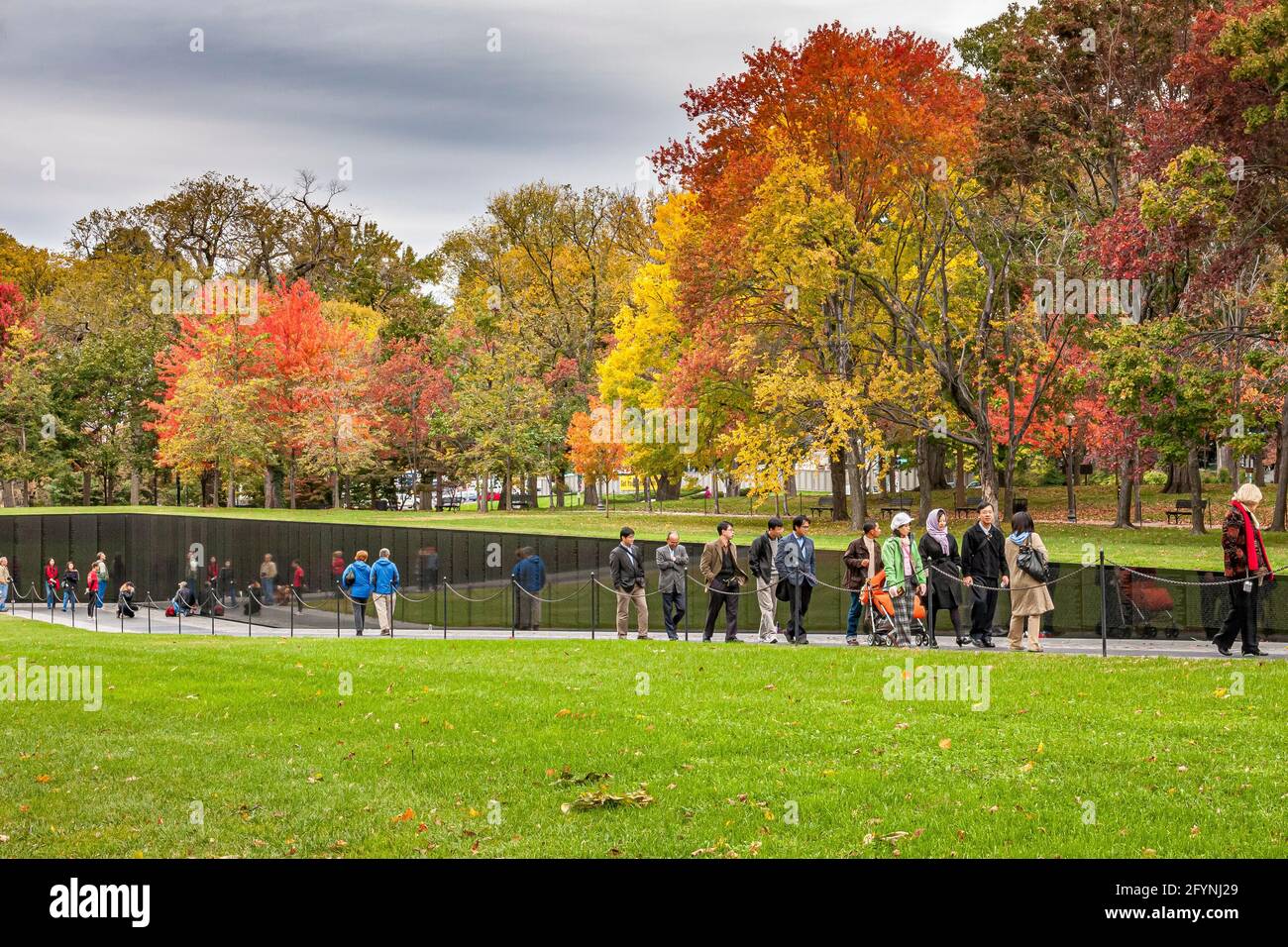 People walking past the granite wall of the Vietnam Veterans memorial inscribed with names of the U.S. armed forces who fought in The Vietnam War Stock Photo