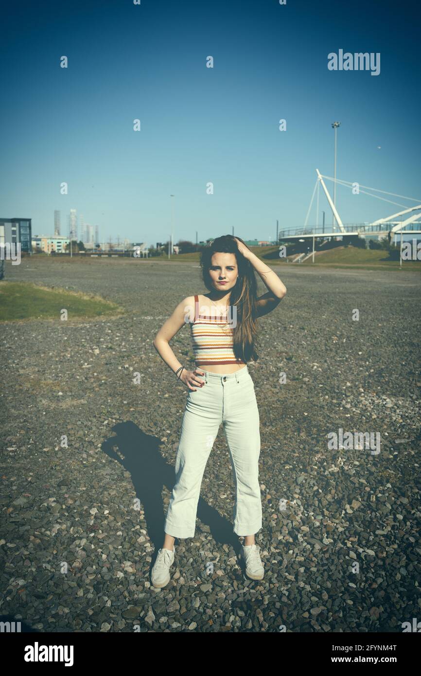 Young brunette woman wearing a crop top with high wasted jeans in a park Stock Photo