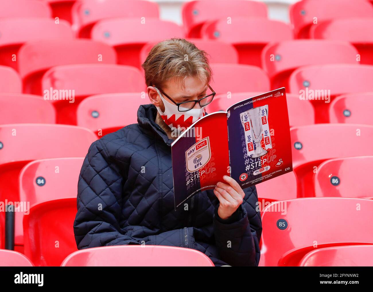 Wembley Stadium, London, UK. 29th May, 2021. English Football League  Championship Football, Playoff Final, Brentford FC versus Swansea City;  Brentford fan reading the match programme inside Wembley Stadium Strictly  Editorial Use Only.