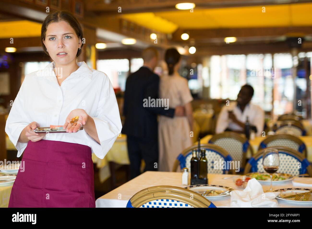 Young waitress expressing displeasure with small tip in cozy restaurant Stock Photo