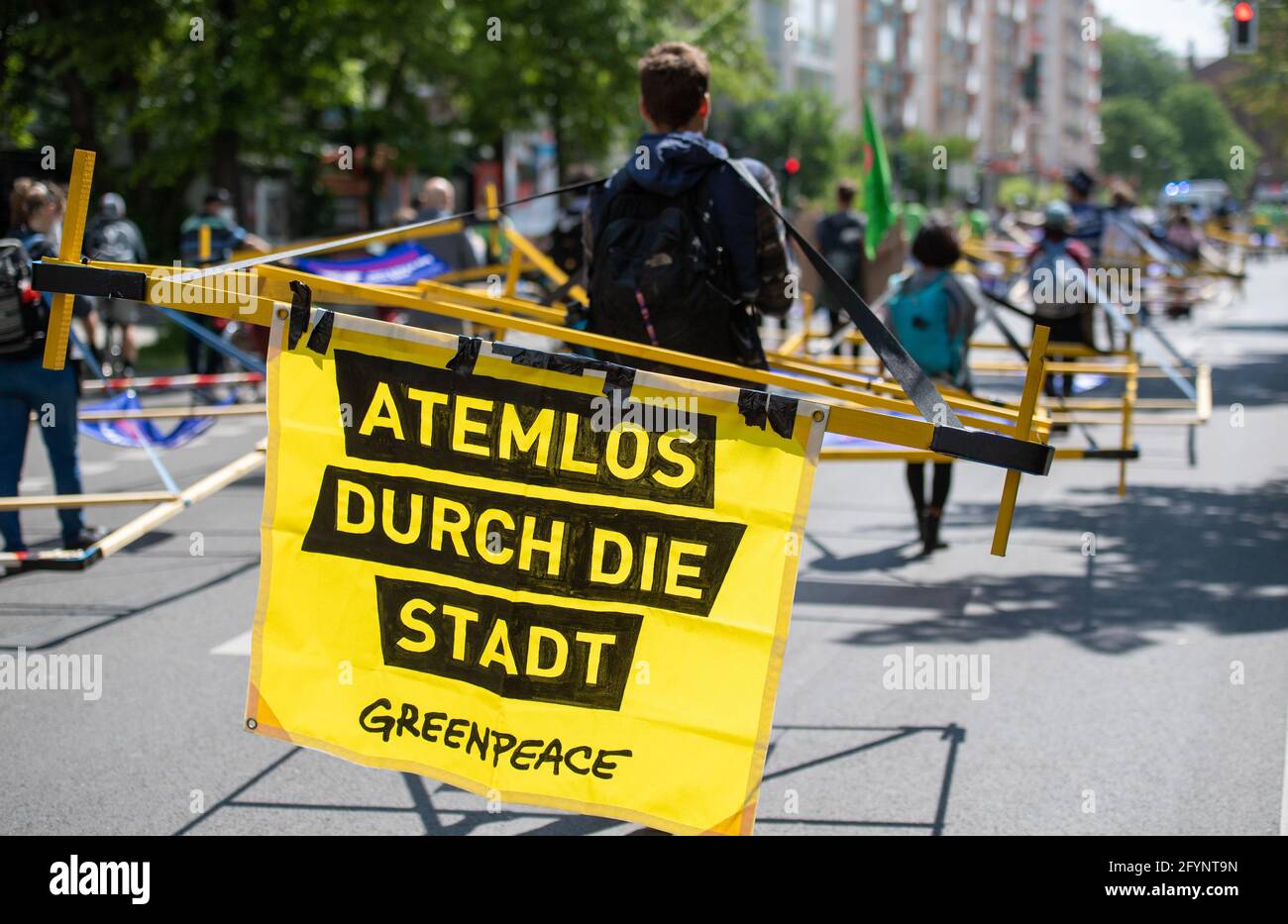 Berlin, Germany. 29th May, 2021. A participant carries a banner with the inscription 'Atemlos durch die Stadt' (Breathless through the city) during an action of 'Volksentscheid Berlin autofrei' and Greenpeace Berlin. During the action, wooden racks, which are supposed to represent the average space consumption of cars, are used to demonstrate against the consumption of space by cars. Credit: Christophe Gateau/dpa/Alamy Live News Stock Photo