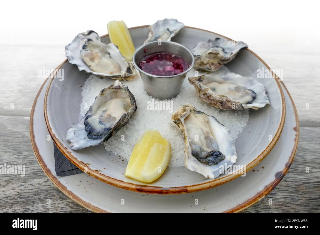 plate with fresh opened oysters and dip on a wooden table, gradient isolated in white back Stock Photo