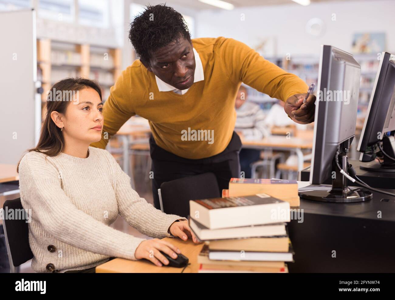 Confident african american man helping young hispanic woman in computer ...