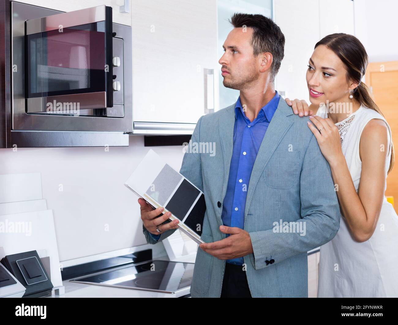 Young glad cheerful  couple choosing microwave in household appliance section in furnishing store Stock Photo