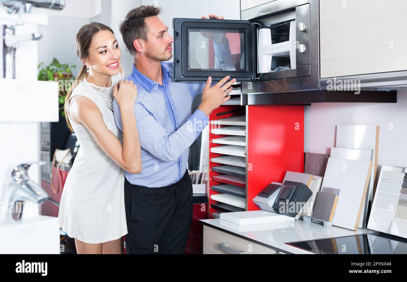 Husband and wife are choosing new microwave in kitchen furnishing store. Stock Photo