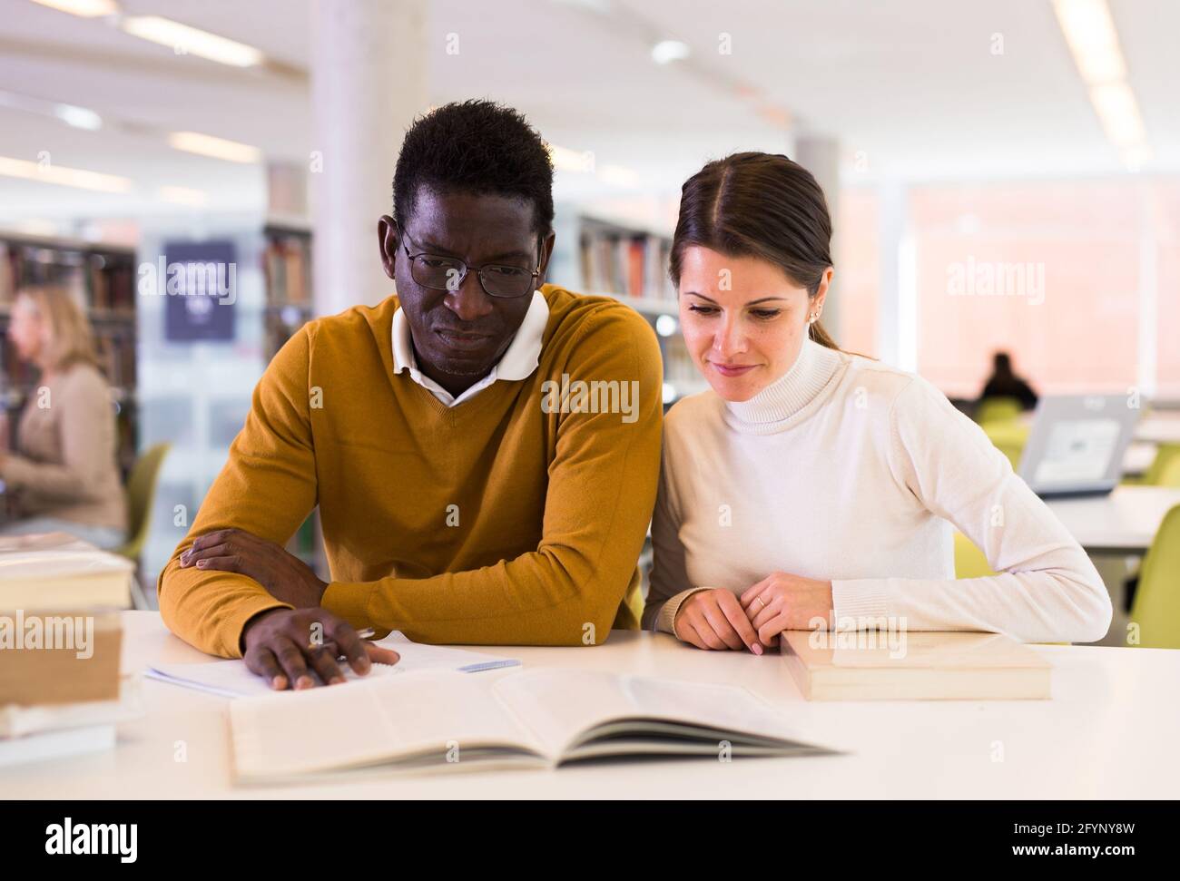 People reading and making notes while preparing for exam in library Stock Photo