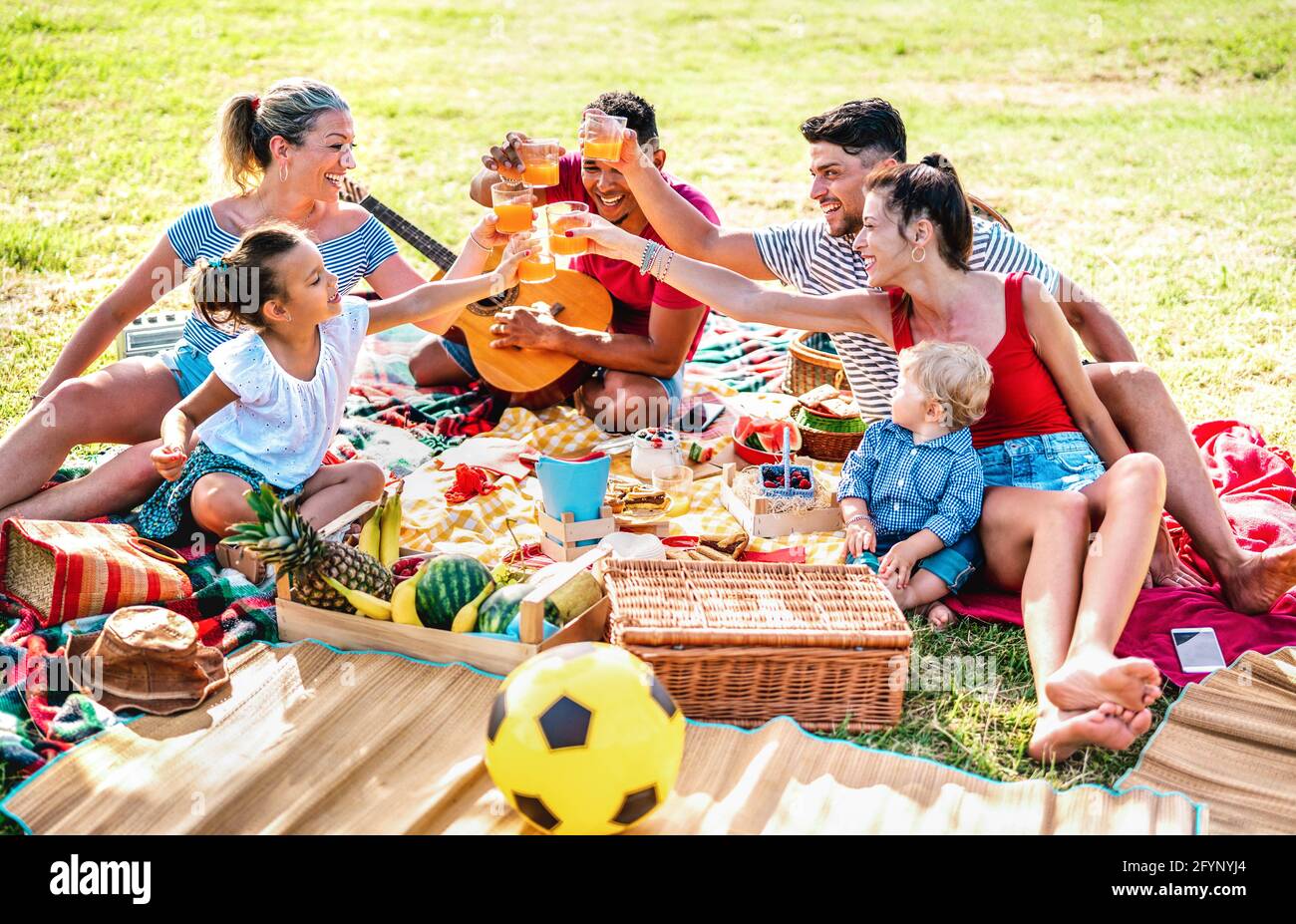 Multiracial families having fun together with kids at pic nic barbecue party - Joy and love life style concept with mixed race people toasting juices Stock Photo