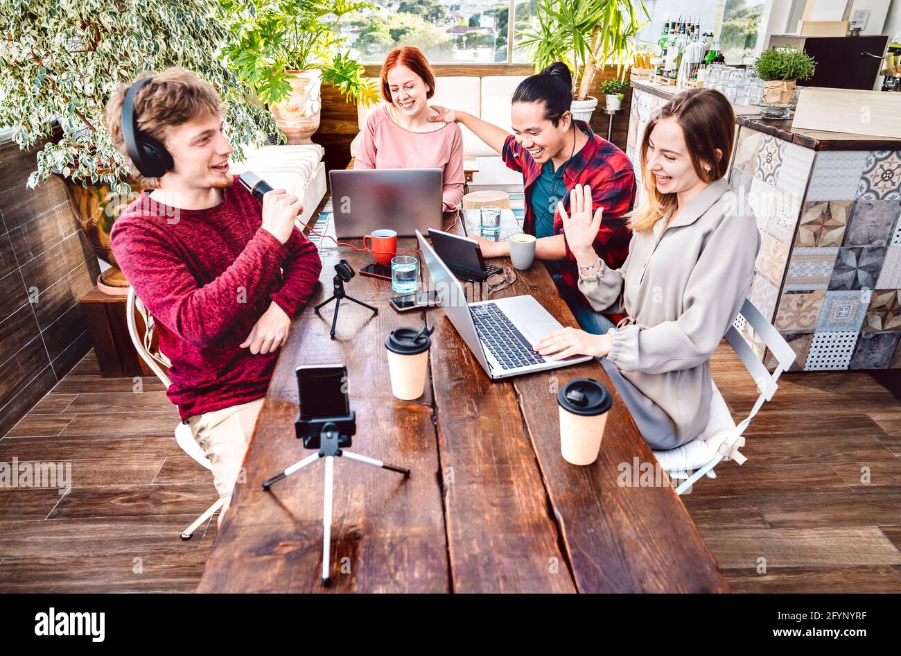 Happy friends sharing content on streaming networks with smart phone cam - Tech life style concept with men and women talking and having fun vlogging Stock Photo