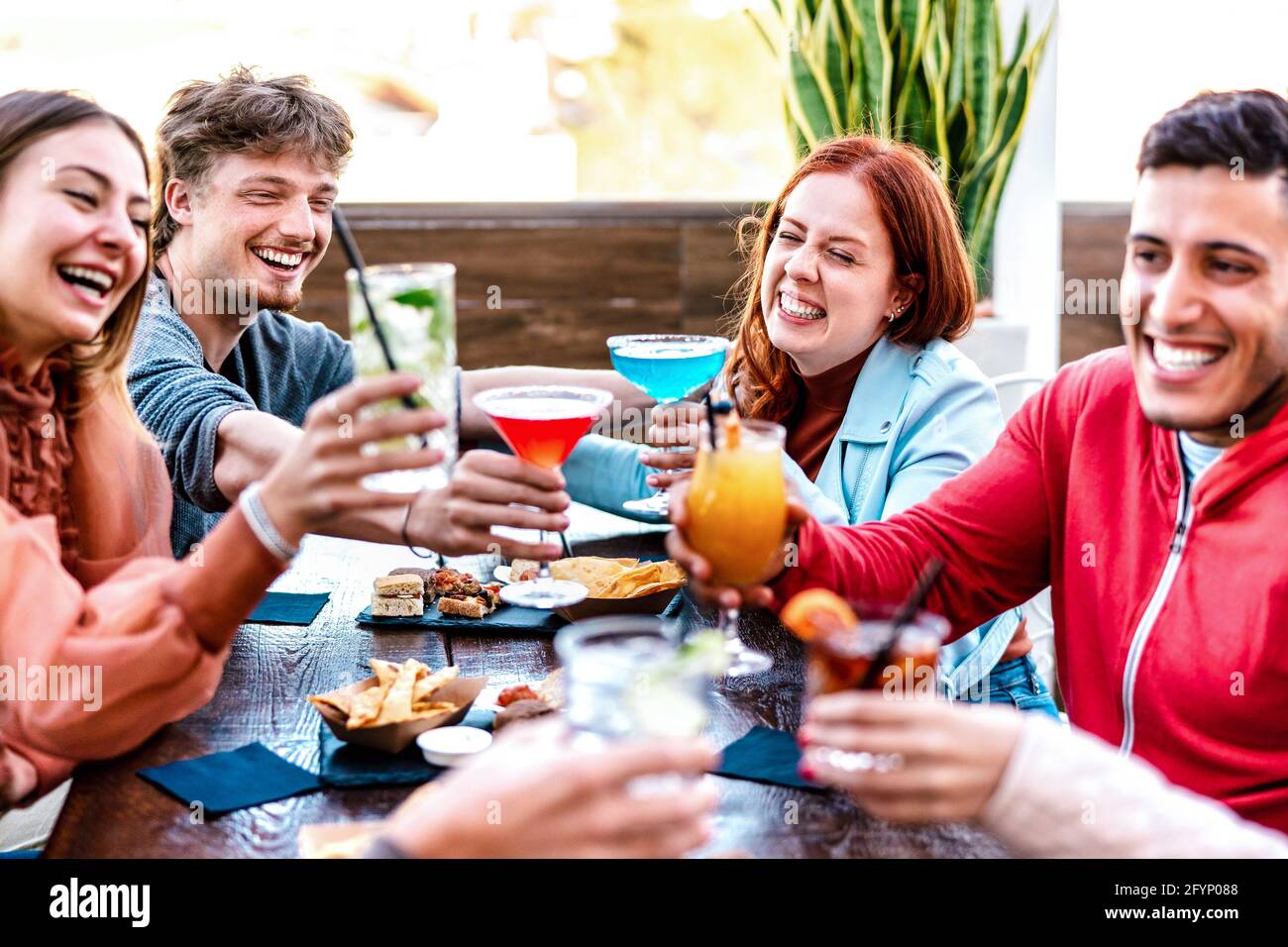 Friends toasting multicolored drinks at fashion cocktail bar restaurant - Life style concept with young people having fun together on happy hour Stock Photo