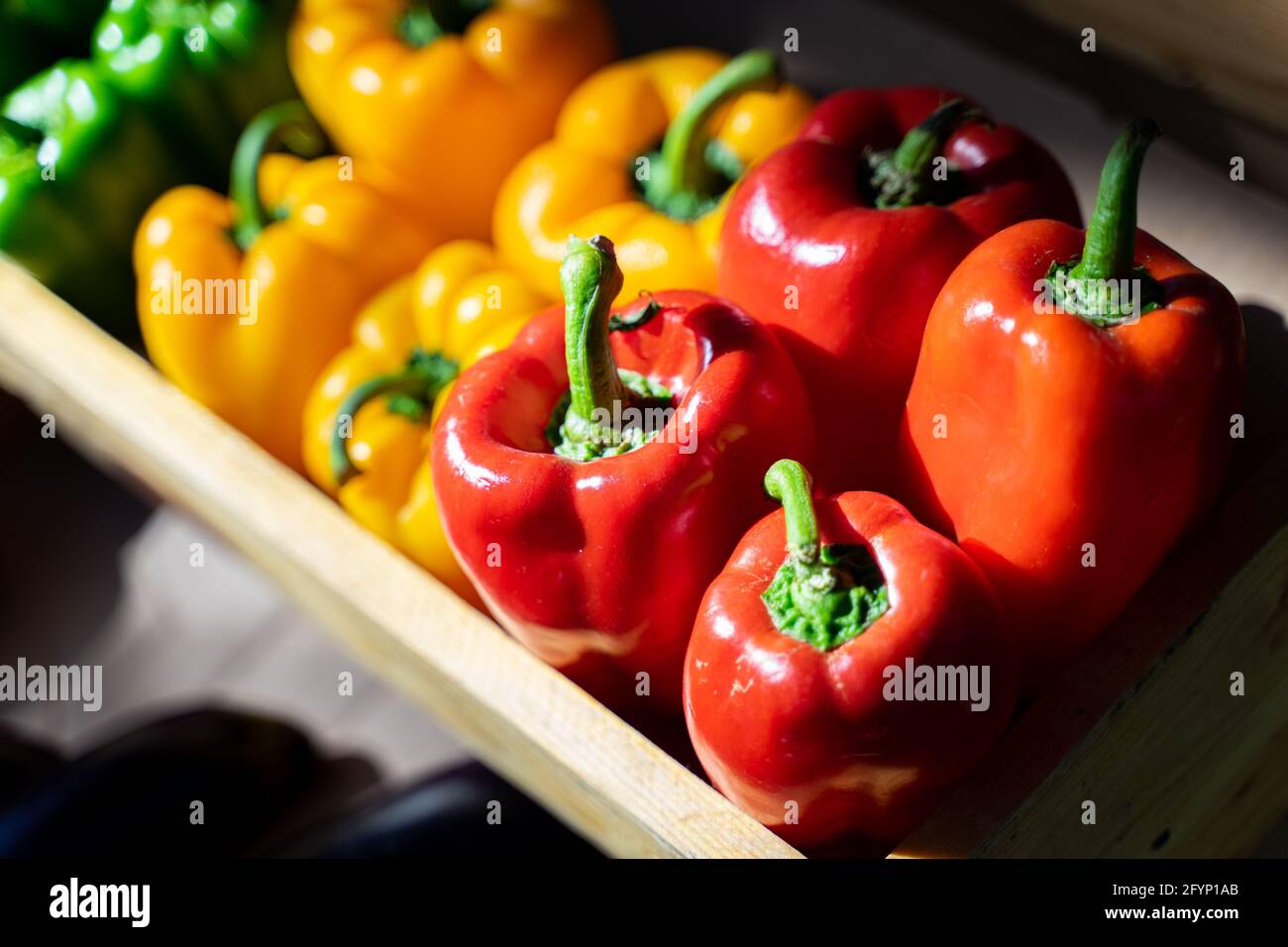 Red, green and yellow bell peppers in the vegetable box at the market ...
