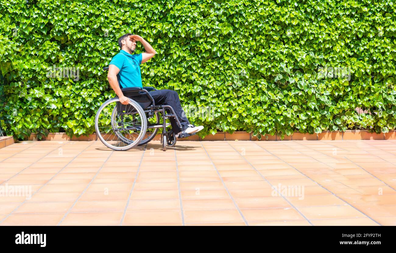 Spanish handicapped man in a wheelchair shielding his eyes against the