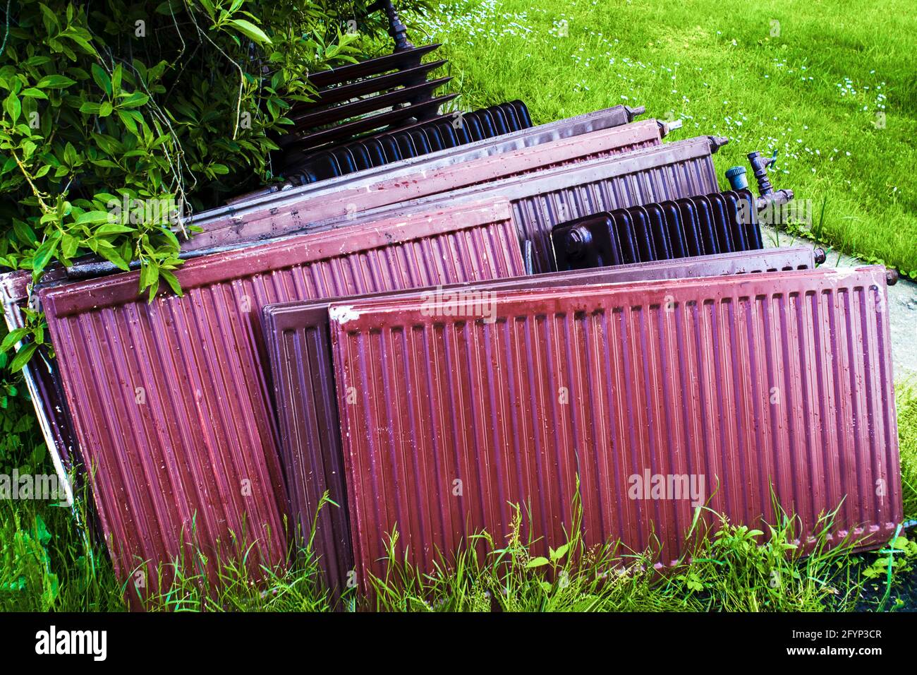 Old heating radiators in the green yard. Replacing used radiators in