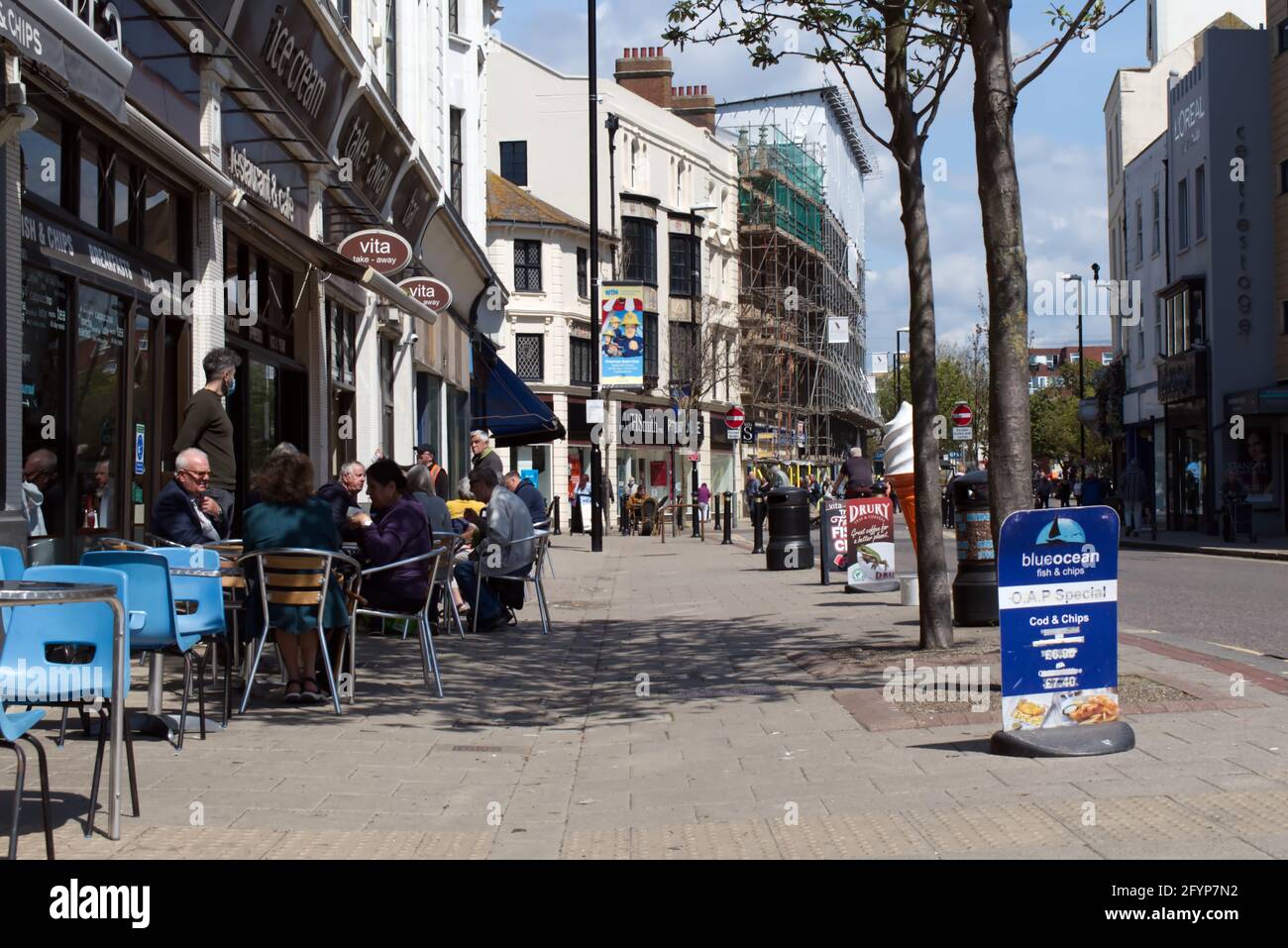 People eating outside of restaurants and cafe on South Street in the town of Worthing West Sussex. Stock Photo