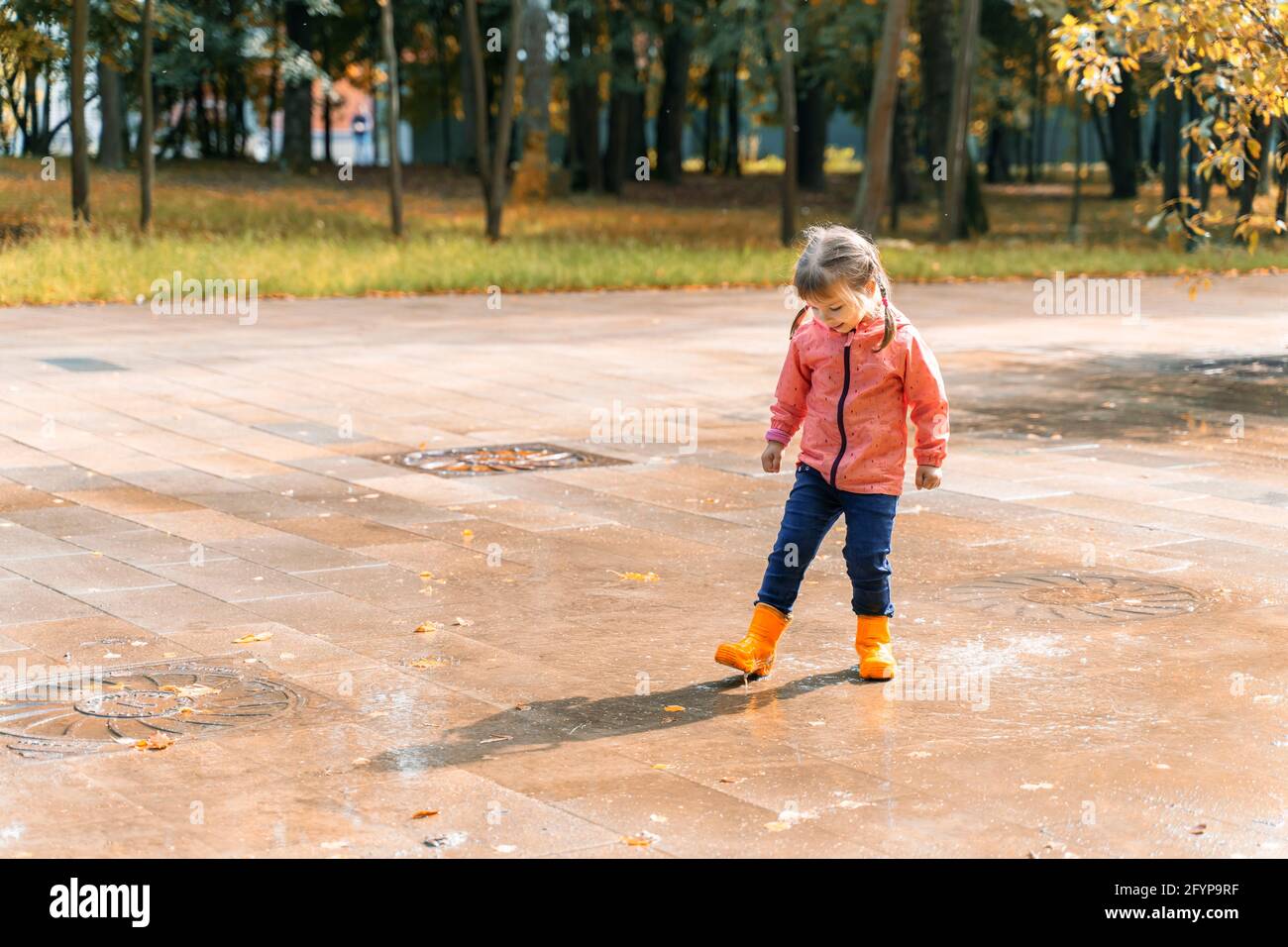 child girl jumping and playing in a puddle after rain Stock Photo - Alamy