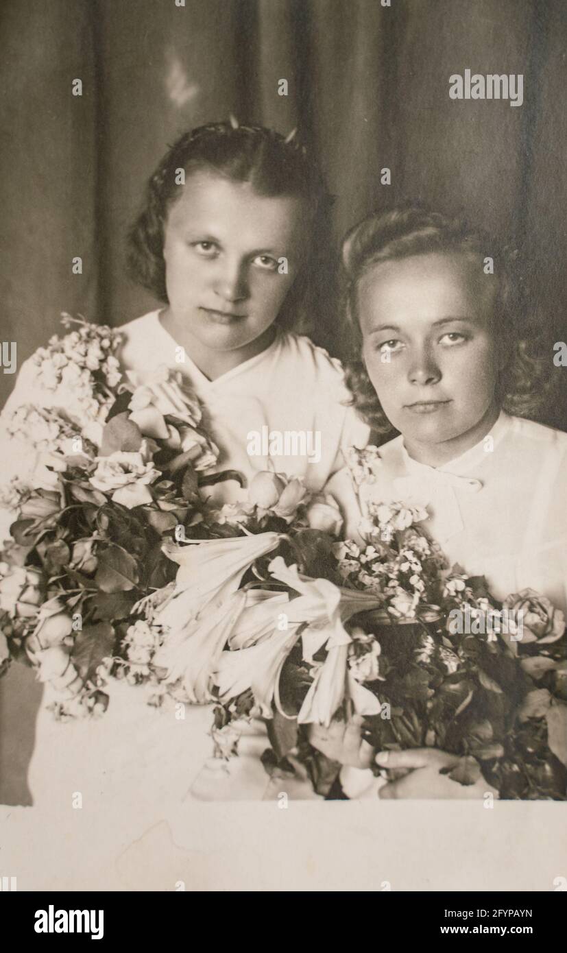 Latvia - CIRCA 1930s: Close up portrait of two woman with flowers in studio. Vintage Art Deco era photo Stock Photo