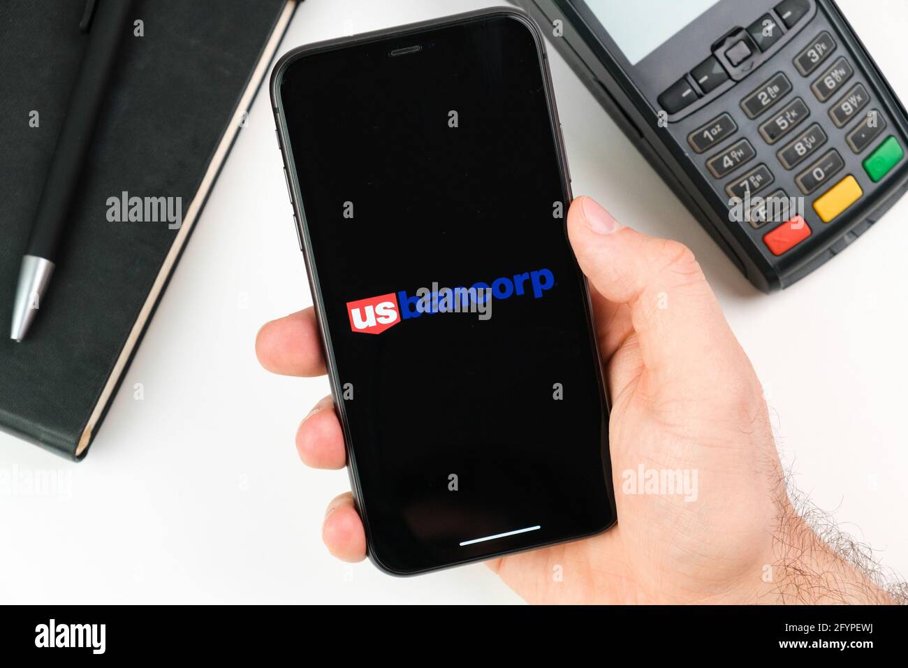 US bank logo on the black smartphone screen in mans hand on the background of payment terminal, May 2021, San Francisco, USA Stock Photo