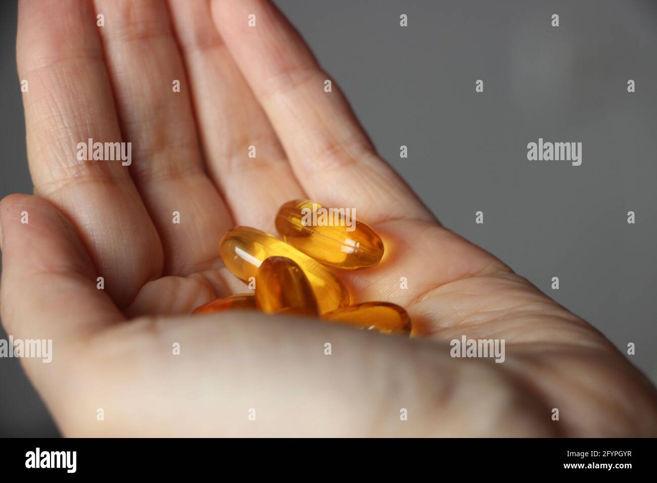 Medicine, nutritional supplements and people concept - close up of hands holding cod liver oil capsules. Hands of a woman holding fish oil Omega-3 cap Stock Photo