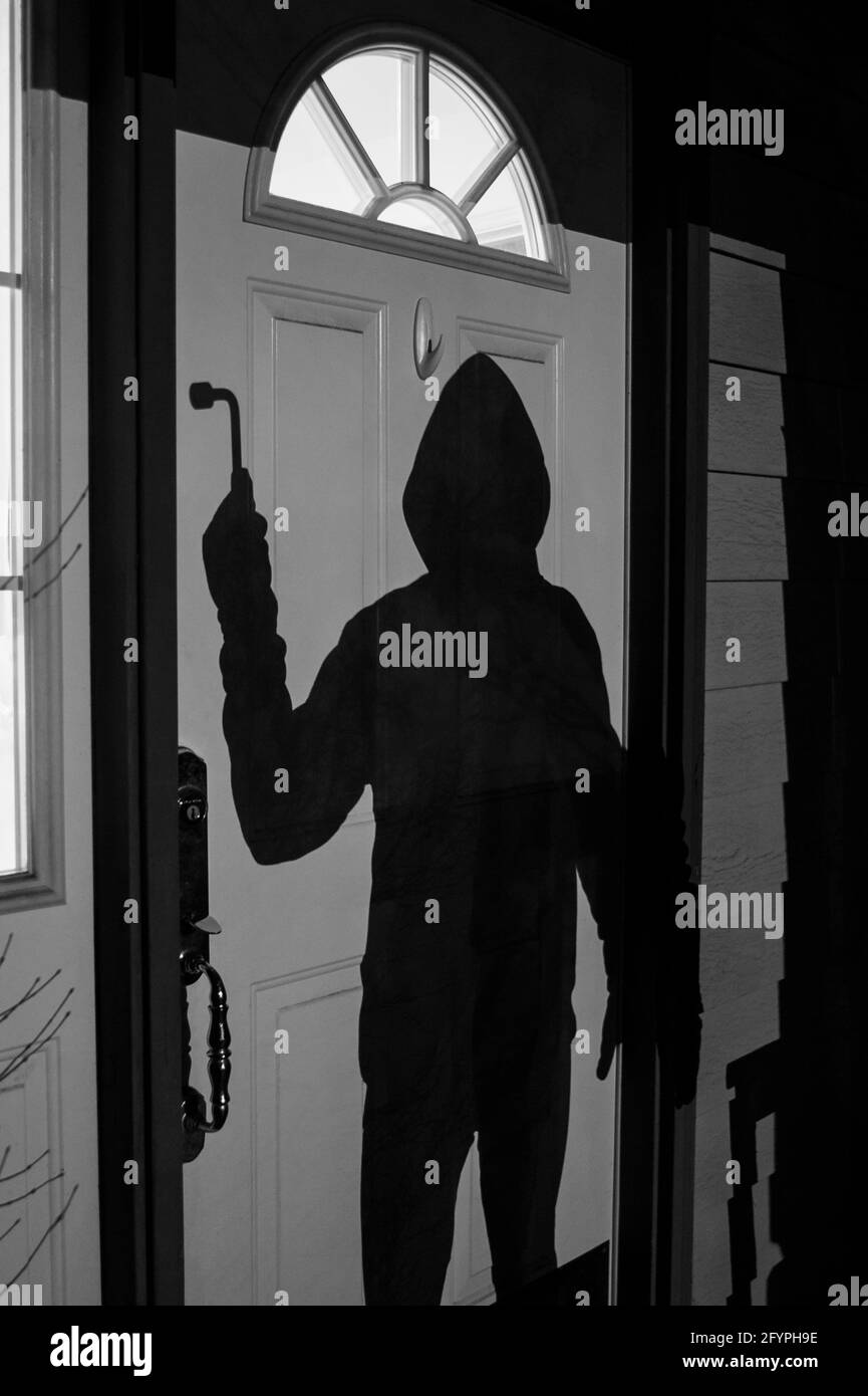 Burglar breaking into home at night standing at the front  door Stock Photo