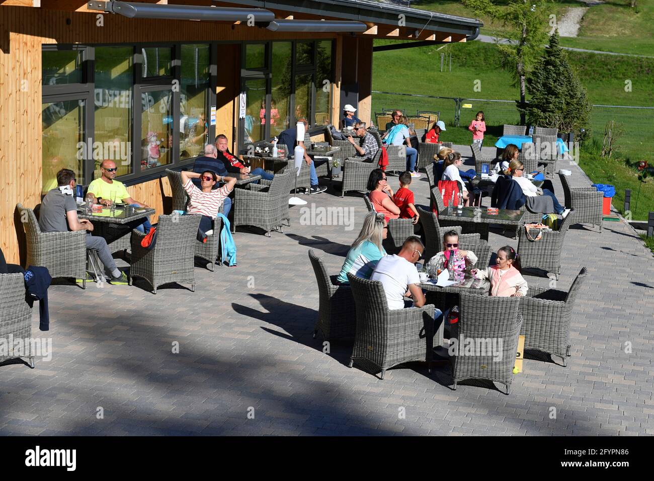Opening of outdoor catering, relaxation and regaining of old freedoms after falling incidence. Guests of a restaurant sit outside on lounge furniture in the sun. Stock Photo