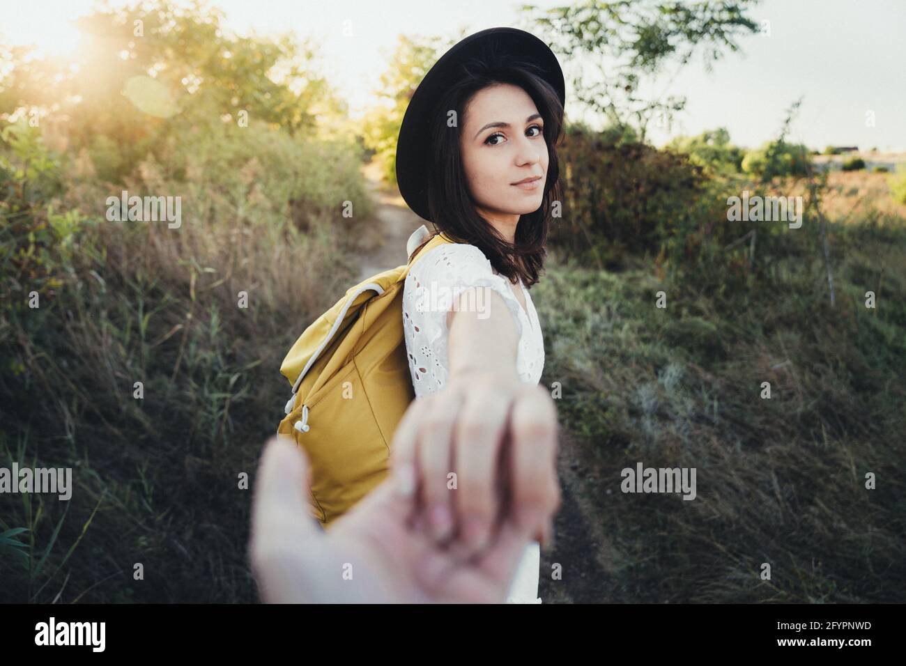 Hiker woman holding man's hand and leading him on nature outdoor. Couple in love. Point of view shot Stock Photo