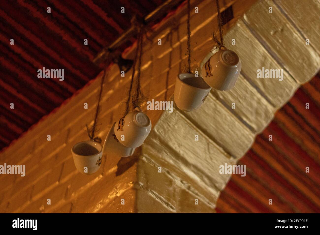 Old mugs on hangers hanging on the chandelier in a room Stock Photo
