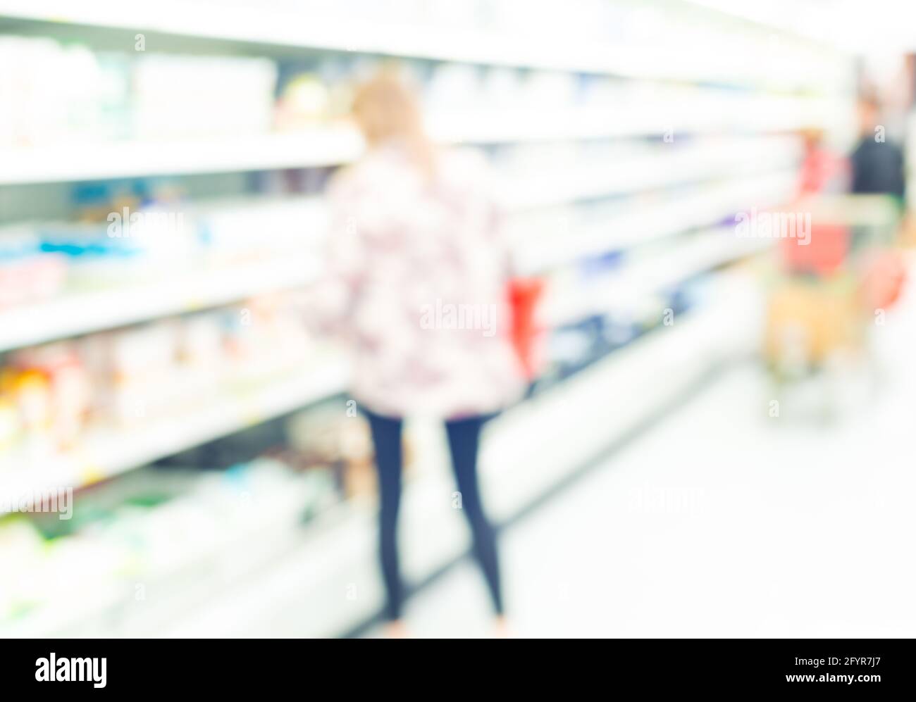 young woman near the dairy racks of supermarket Stock Photo