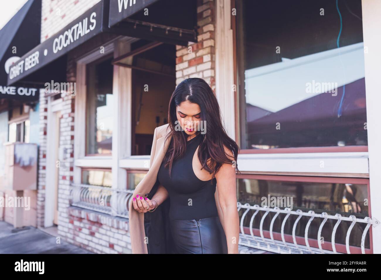 Serious woman walking in front of restaurant with brick walls. Stock Photo