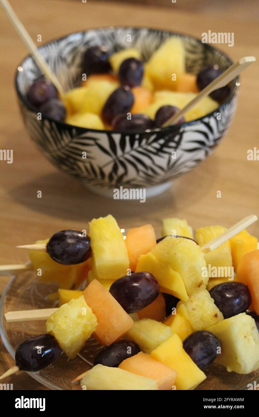 Juicy fruits on wooden dowels and a fruit salad on a wooden table Stock Photo