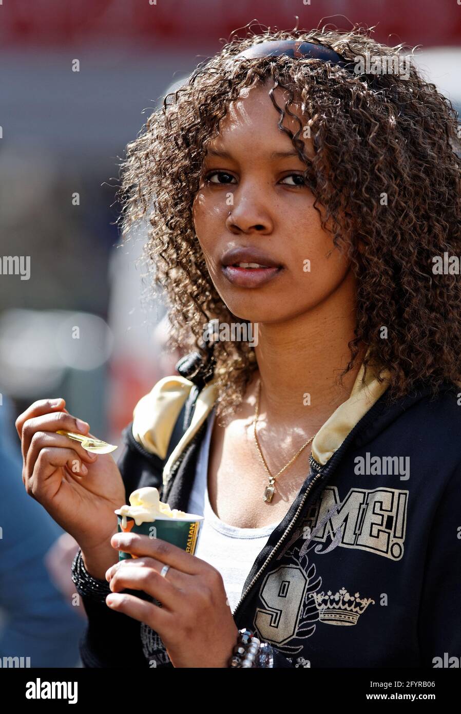 portrait de jeune fille aux cheveux noir bouclés mange un cornet de glace Stock Photo