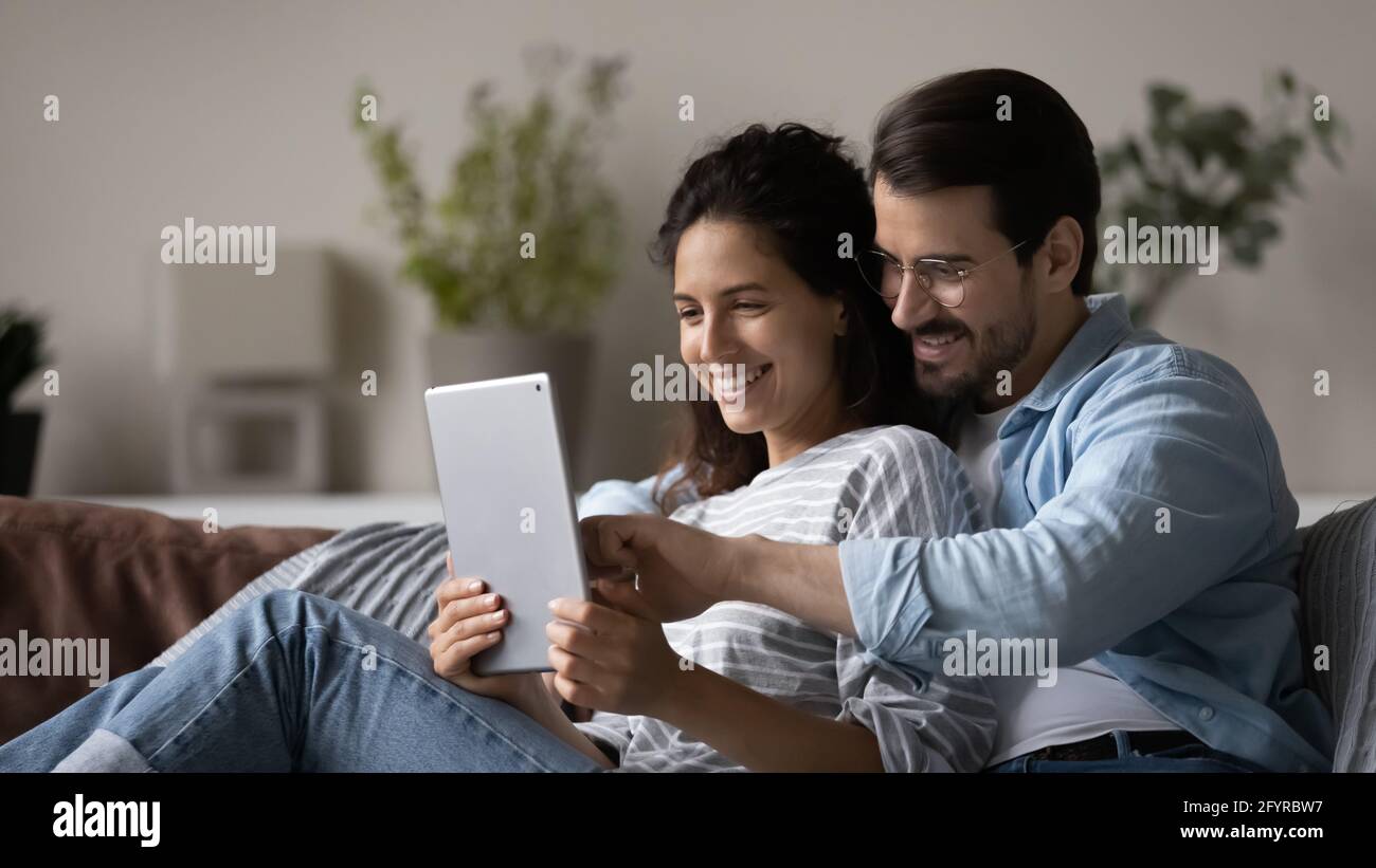 Smiling multiracial couple use tablet talk on webcam call Stock Photo