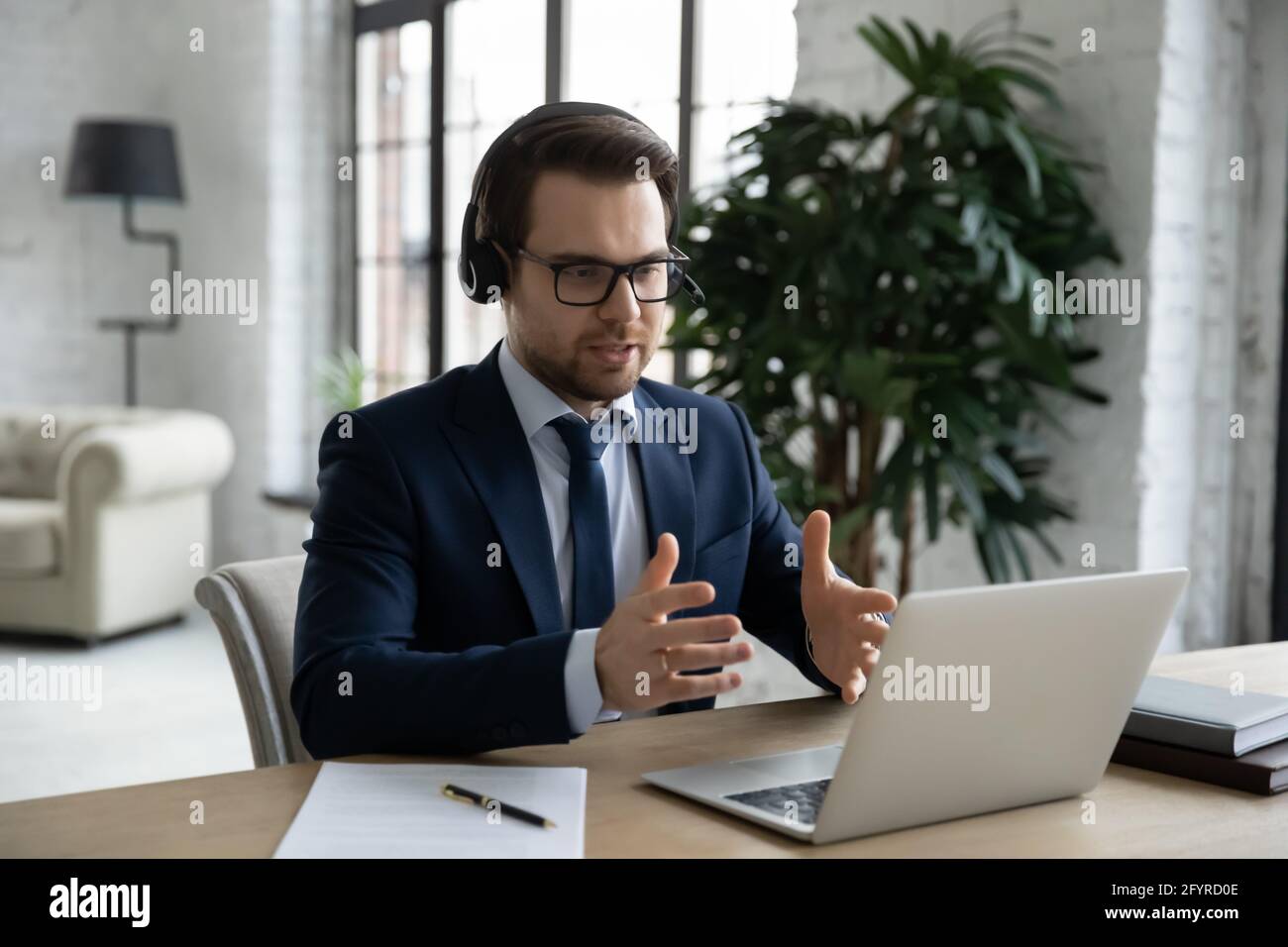 Manager in headset using laptop for video call, giving consultation Stock Photo