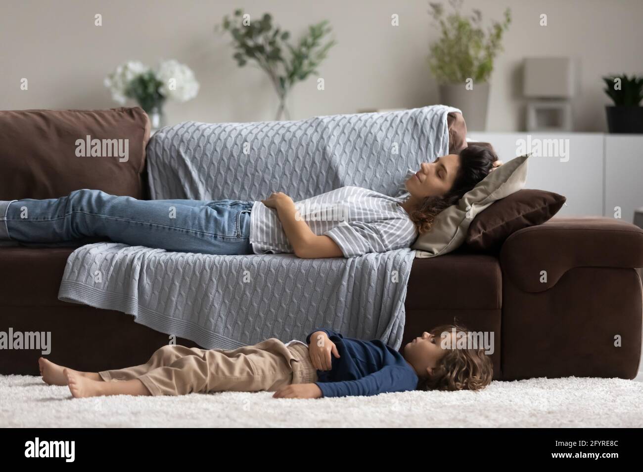 Tired young mom and small kid fall asleep at home Stock Photo