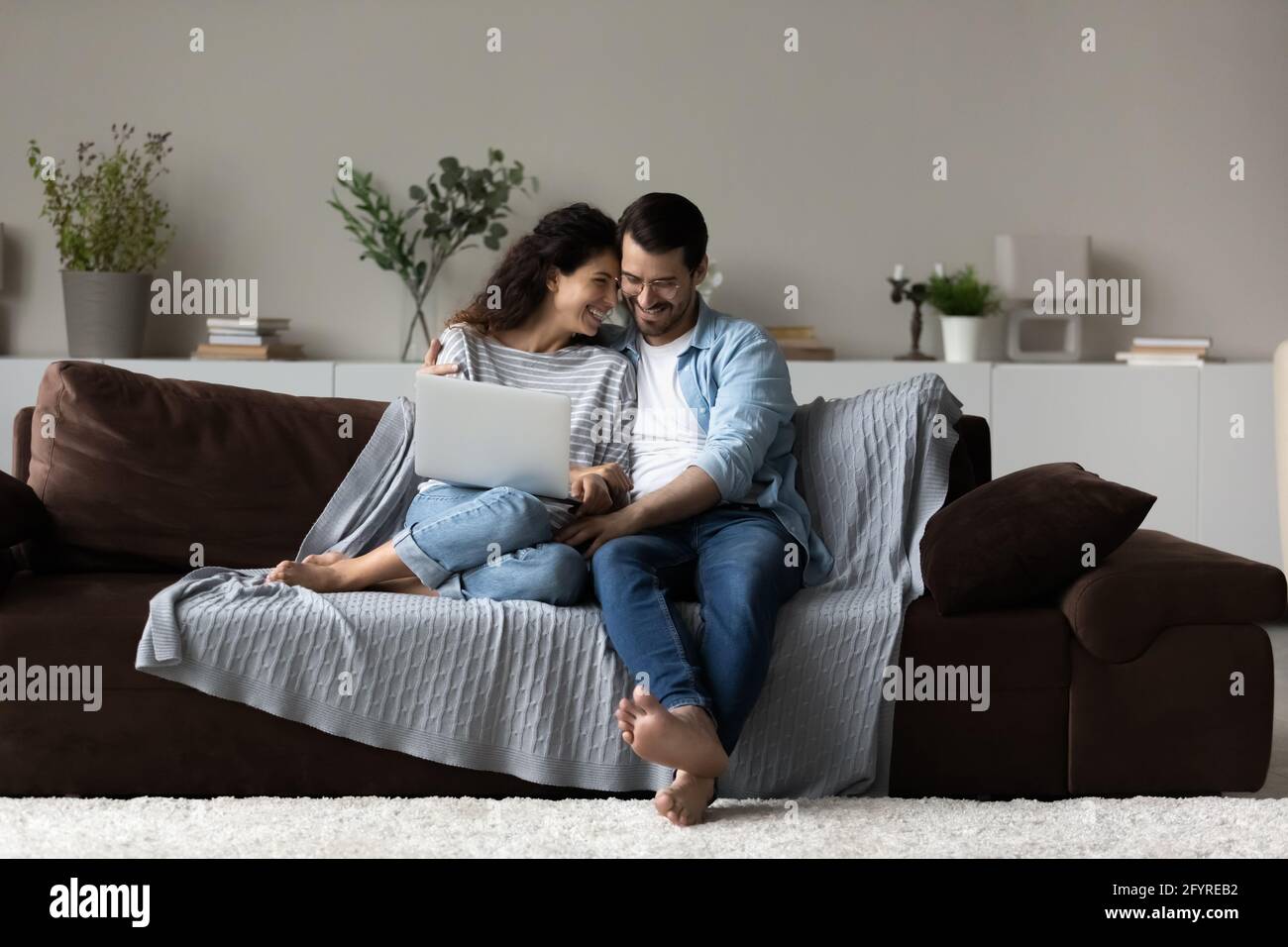 Happy multiracial couple relax at home with laptop Stock Photo
