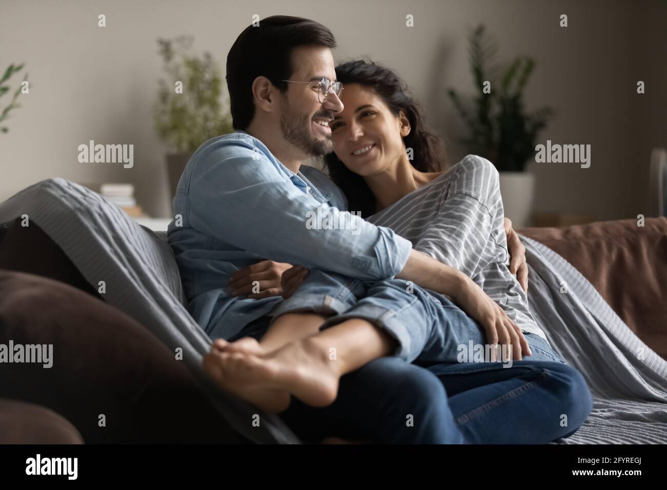 Happy multiracial couple relax at home hugging Stock Photo