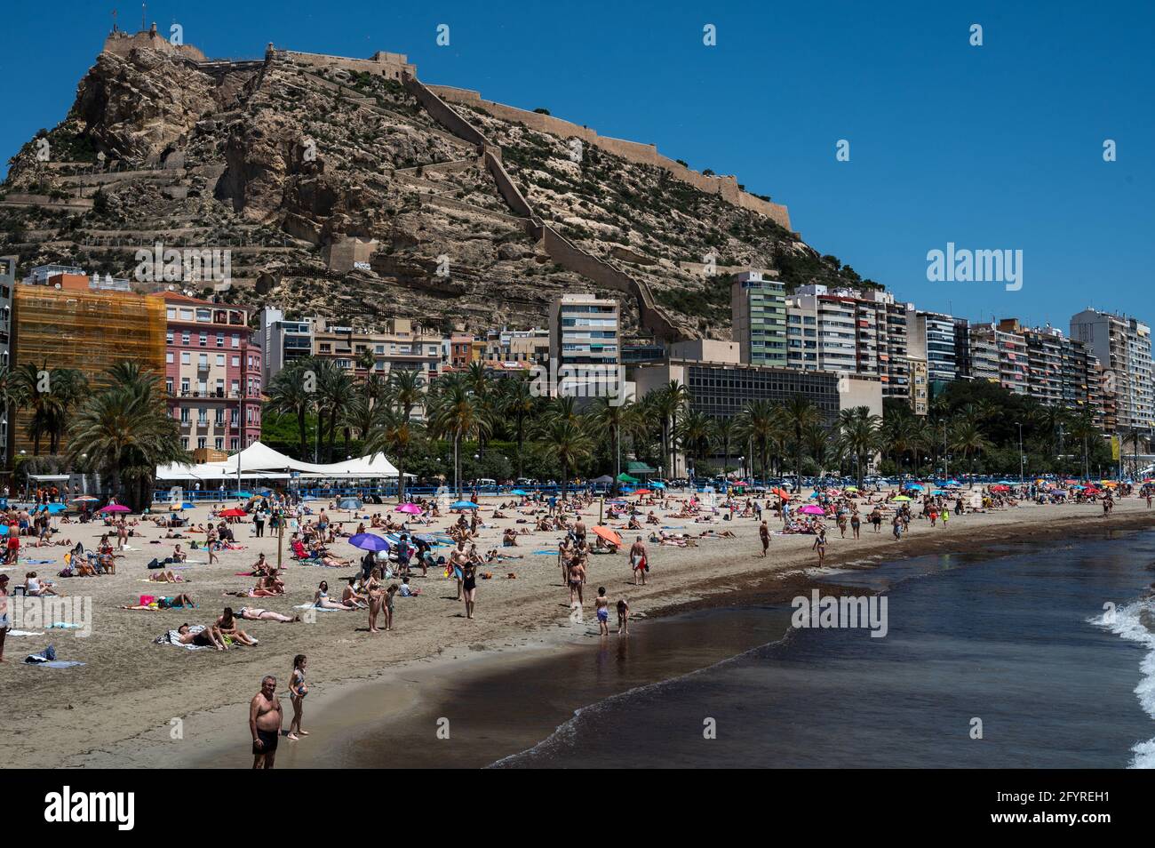 Alicante, Spain. 29th May, 2021. People enjoy high temperatures in a crowded El Postiguet Beach of Alicante. The Valencian Community released this Monday new restriction measures against the coronavirus (covid-19), among others, on the beaches it will no longer be necessary to wear a mask in the rest periods before or after bathing and respecting the minimum distance of 1.5 meters with other people who are not living together, with a maximum group of 10 people. Credit: Marcos del Mazo/Alamy Live News Stock Photo