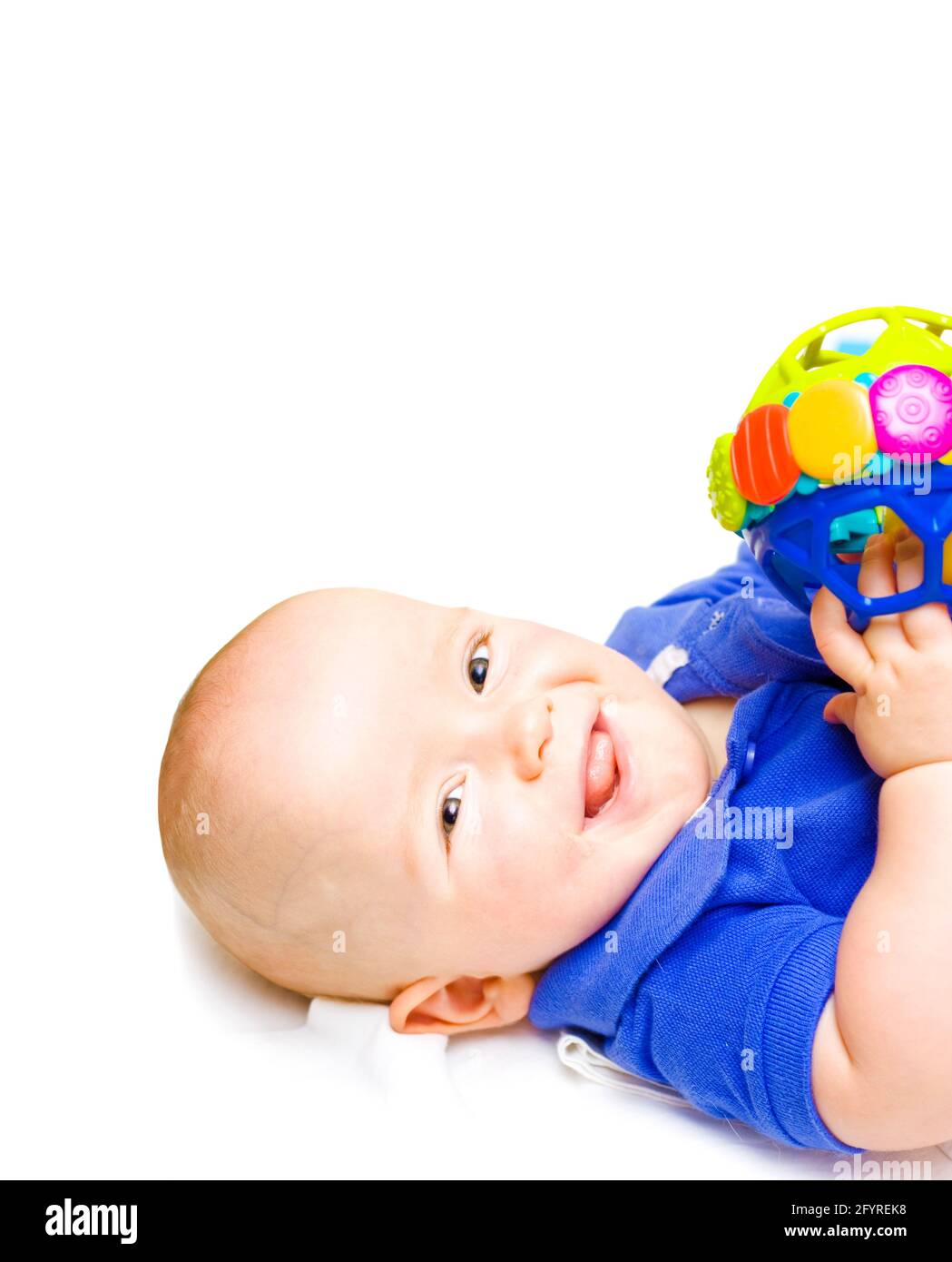 Gurgling Happy Baby With Toy, baby lying on his back witha contented happy expression while playing with a colourful toy, studio close-up on white Stock Photo