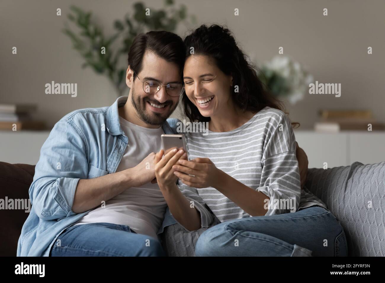Smiling multiracial couple have fun using cellphone Stock Photo