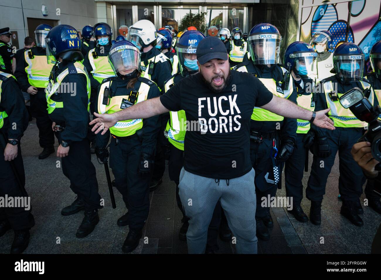 Manchester, UK. 29th May, 2021. A protester stands in front of the police as they try to hold back people from storming the Westfield shopping centre during a anti-lockdown protest. The number of people attending the protests has increased month on month since the introduction of the COVID-19 restrictions. Credit: Andy Barton/Alamy Live News Stock Photo