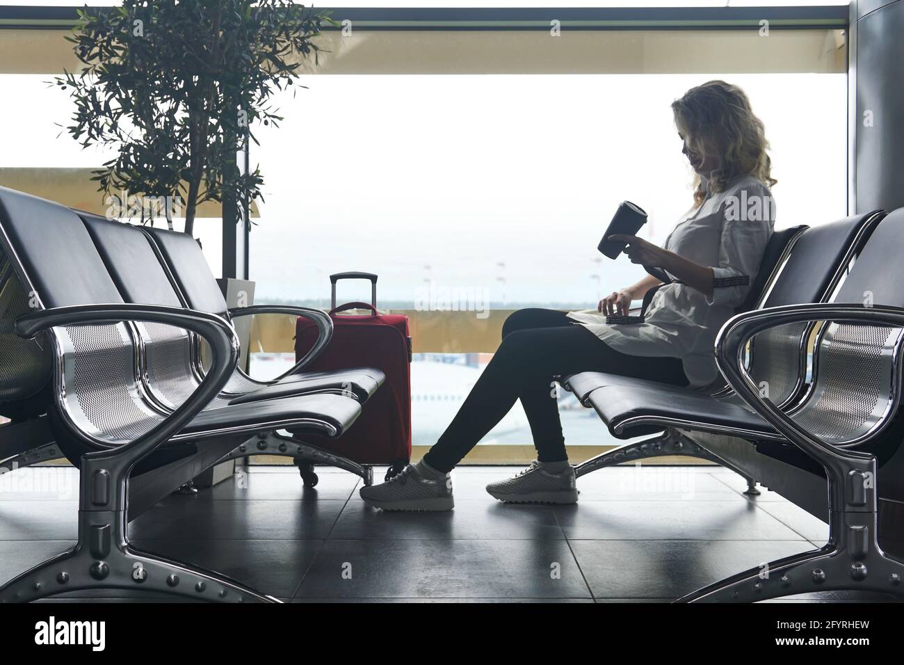 young woman tourist with suitcases sits in the waiting room of the airport and is waiting for the flight Stock Photo