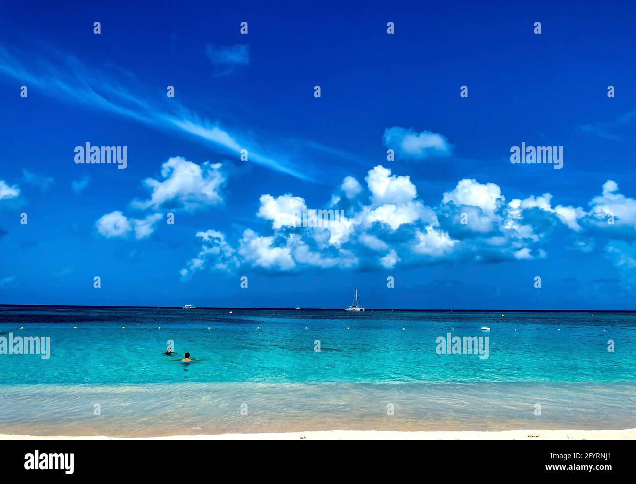 Sailboat on the horizon off the beach at Grand Cayman Island. Stock Photo