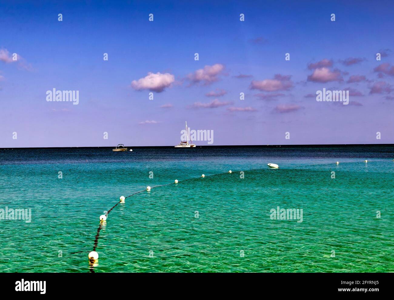 Sailboat on the horizon off the beach at Grand Cayman Island. Stock Photo