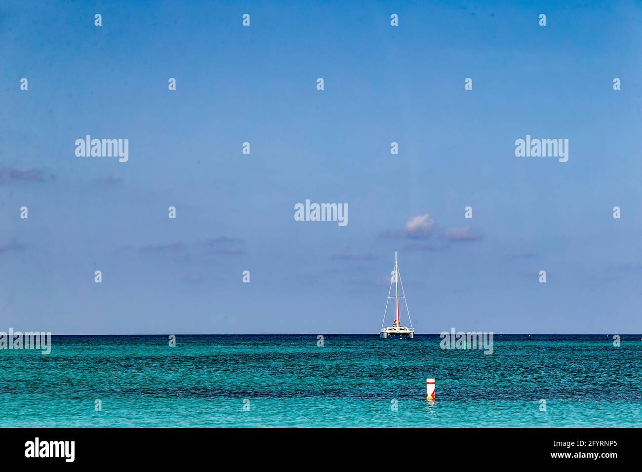 Sailboat on the horizon off the beach at Grand Cayman Island. Stock Photo