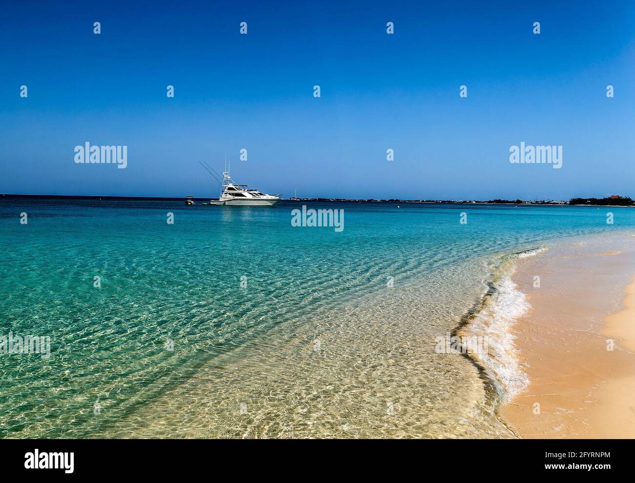 Sailboat on the horizon off the beach at Grand Cayman Island. Stock Photo