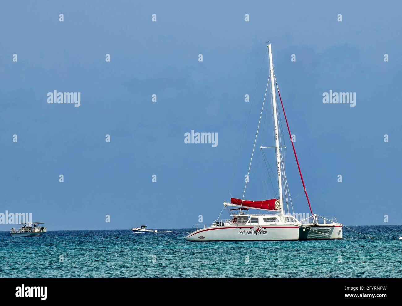 Sailboat on the horizon off the beach at Grand Cayman Island. Stock Photo