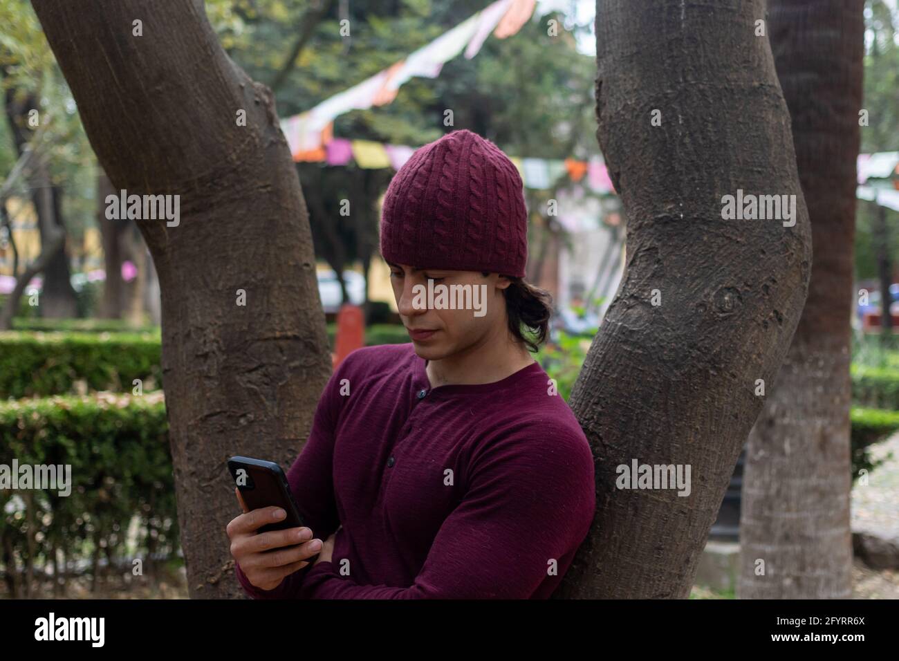Young hispanic man with beanie looking at his cellphone Stock Photo